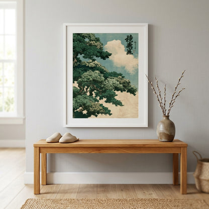 A framed art print featuring a Japanese-style tree and clouds in soft teal, green, cream, and black tones, displayed on a light gray wall above a wooden bench in a styled interior.
