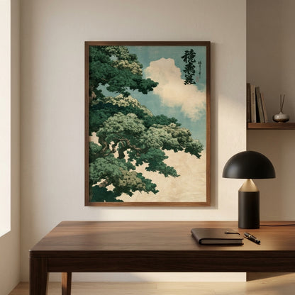 A framed Japanese-style art print featuring a green tree and clouds hangs on a beige wall above a wooden desk with a black lamp and notebook.