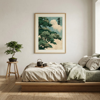 A framed vertical art print depicting a traditional Japanese landscape with green trees and a pale blue sky, hanging on a light beige wall above a minimalist wooden platform bed in a styled bedroom.