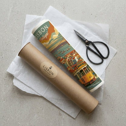 A Lisbon travel poster print in a kraft cardboard tube, displayed with black-handled scissors on white tissue paper over a light gray textured surface.